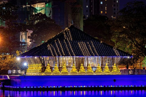A temple shrouded in lights with golden Buddha statues at night, The Seema Malaka Temple in Colombo