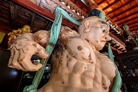 Large wooden sculpture with Buddhist theme in traditional setting, statues of gods in Colombo