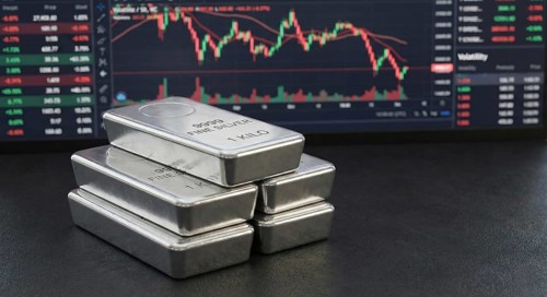 Stacked 99.99% fine silver bars are displayed in front of a digital financial chart, symbolising