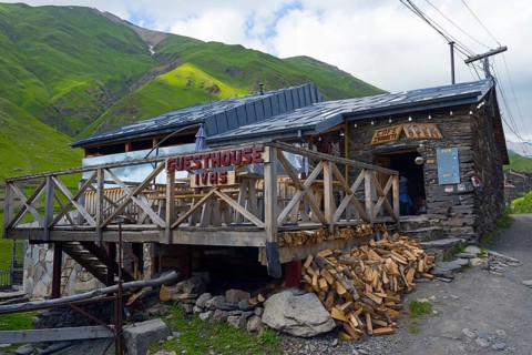 Guesthouse with wooden veranda in a mountain landscape under a cloudy sky, Cafe Svaneti, Ushguli,