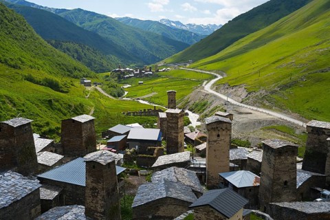 Village with several towers and a road in lush mountain scenery, defensive towers, Ushguli,