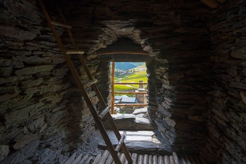 Stone interior of a defence tower with ladder and view of a green valley, in the tower of Queen