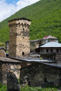 Historic stone building with a high tower in a green mountain valley, defensive towers, Ushguli,