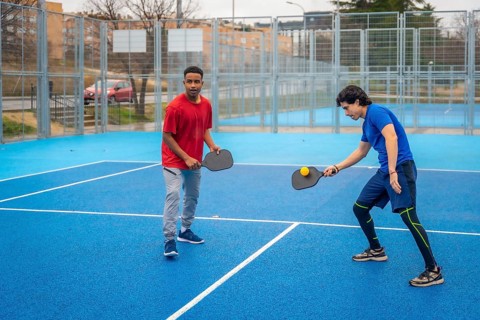Two men intensely competing in pickleball on a vibrant blue outdoor court, focused and athletic as