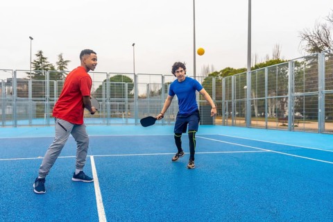 Two young menone african american, one caucasiancompete in an energetic outdoor pickleball rally,