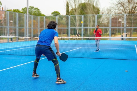 Two male athletes playing an intense pickleball game on a vibrant blue court, holding paddles and