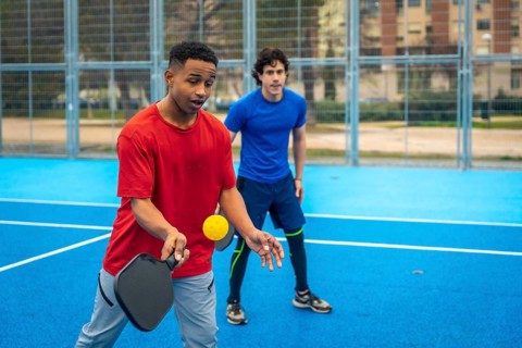 Young diverse men playing pickleball, engaging in active recreation and enjoying the outdoor sports