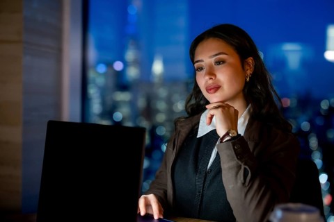 Young businesswoman with elegant hairstyle working late hours, researching or analyzing data on her