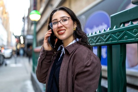 Young businesswoman standing in new york city, actively communicating on her mobile phone while