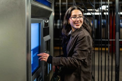 Young businesswoman with glasses and dark coat smiling, looking over her shoulder while interacting