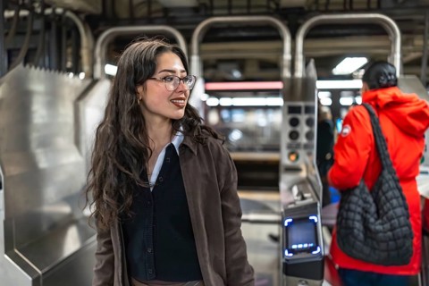 Young businesswoman enters a manhattan subway station, scanning her card at the turnstile during a