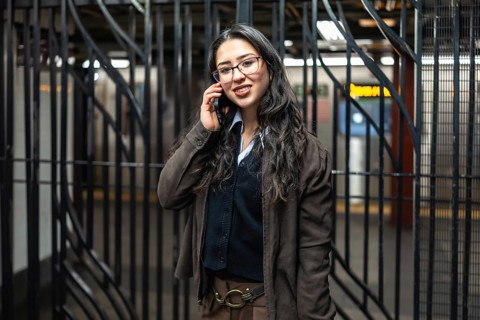 Young businesswoman standing in a new york city subway station, smiling while having a business