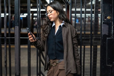 Young businesswoman standing in a new york city subway station, checking her mobile phone while