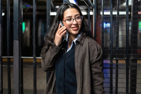 Young professional businesswoman smiling, talking on a mobile phone, and standing on a new york