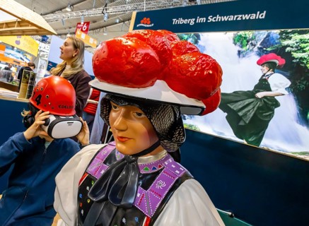 Tradition and progress. A young trade fair visitor wearing 3D glasses next to a model of a woman