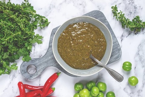 Tkemali sauce, made from green cherry plum, with ingredients on the table, top view, Georgian