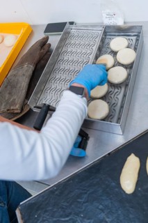 Hands a person places dough circles on a tray with patterns to prepare, bake rolls, Haselstaller