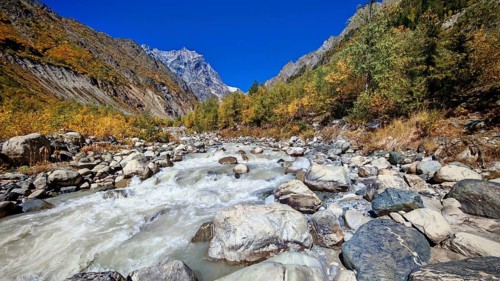 A rushing river in a mountainous fall landscape with clear blue sky, Mestia, Georgia