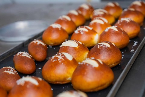 Several golden brown pretzel rolls with salt on a baking tray in the bakery, bake rolls,