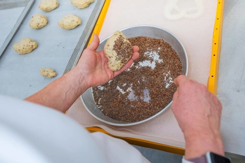 A baker sprinkles a dough with linseed on a baking tray, bake rolls, Haselstaller Hof, Gechingen,