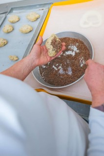 A baker prepares dough by sprinkling it with linseeds, baking rolls, Haselstaller Hof, Gechingen,
