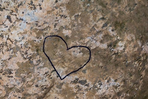 Close-up of painted black heart outline symbol on tanned nuanced rock surface, Quebec, Canada