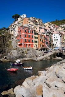 Colourful houses under blue sky, view of the fishing village of Riomaggiore, boats in the harbour,