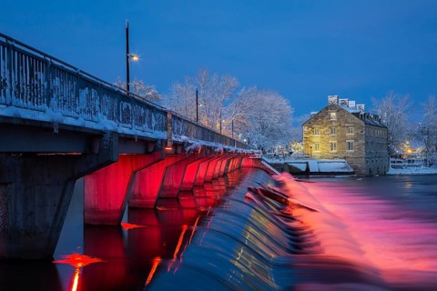 Illuminated Moulin Neuf water flow control dam and walkway over Des Mille-Iles river plus New Mill