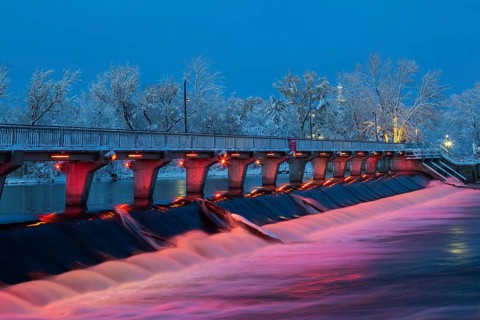 Illuminated Moulin Neuf water flow control dam and walkway over Des Mille-Iles river with first