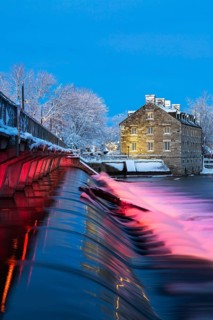 Illuminated Moulin Neuf water flow control dam and walkway over Des Mille-Iles river plus New Mill