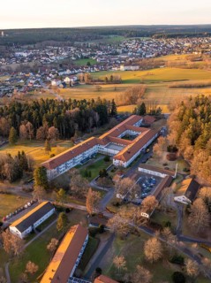 A bird's-eye view of a village with extensive fields and buildings at winter sunset, Rehab Clinic,