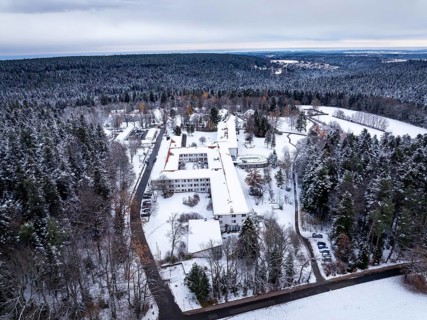 Snowy landscape with buildings surrounded by thick forests and a wide sky, rehab clinic, Schömberg,