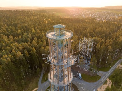 A high observation tower in the forest, surrounded by trails and illuminated by evening light,