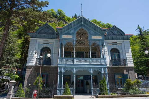 Magnificent historical architecture with an ornate blue veranda nestled in green nature, old villa