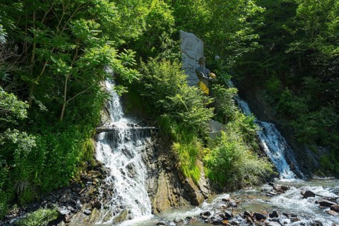 Double waterfall in dense vegetation flows into a river, Borjomi resort, Borjomi, waterfall in