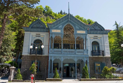 Historic blue building with abundant decorations and trees in the foreground, old villa villa of