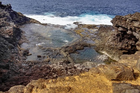 Rocky coastline with clear turquoise water pools and nearby waves, Yaiza Lanzarote