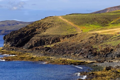 Cliff landscape with green path along the coast and views of the sea, Puerto Calero Lanzarote