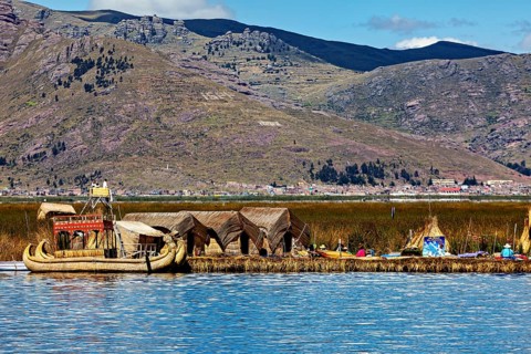 Reed boats and huts on a lake with mountains in the background, The floating reed islands of the