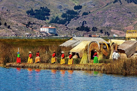 Women in traditional clothing in front of reed huts on an island in the lake, The floating reed