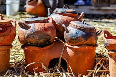 Clay pots and cooking areas arranged on a straw bed with rustic charm, The floating reed islands of