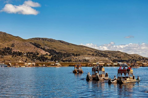 Traditional boats and people on a lake with a sweeping view of the shore, The floating reed islands