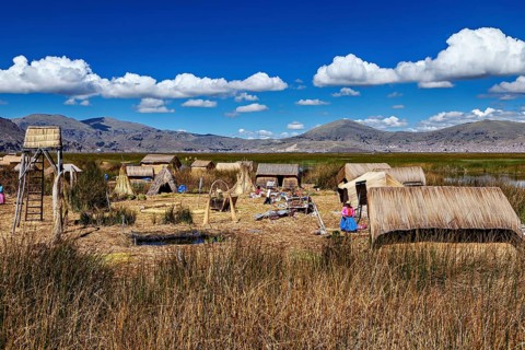 Reed village surrounded by mountains and under a clear blue sky, The floating reed islands of Uros