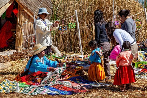 People and children sell and look at crafts in a village made of straw huts, the floating reed
