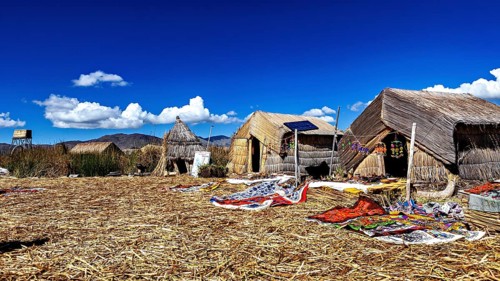 Traditional thatched huts on an island under a clear sky, The floating reed islands of the Uros in