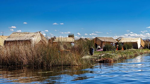 Rows of reed huts along a lake under clear blue skies, The floating reed islands of the Uros in