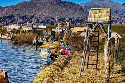 Handmade boats and huts on a lake surrounded by natural scenery, The floating reed islands of the