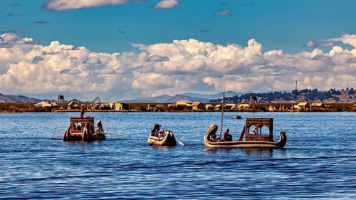 People ride in artfully designed reed boats on a wide lake, The floating reed islands of the Uros