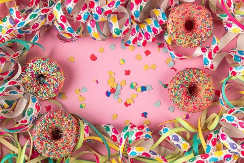 Donuts, streamers and scattered confetti on a pink background, Mardi Gras