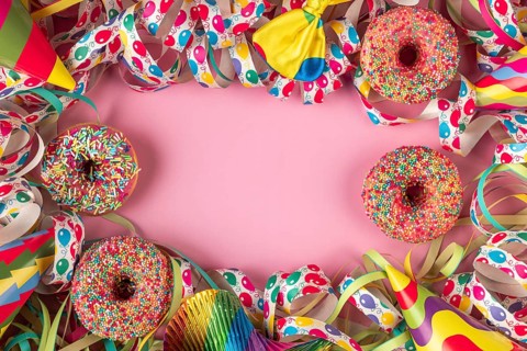 Colourful donuts and streamers with party hats frame a pink area, carnival